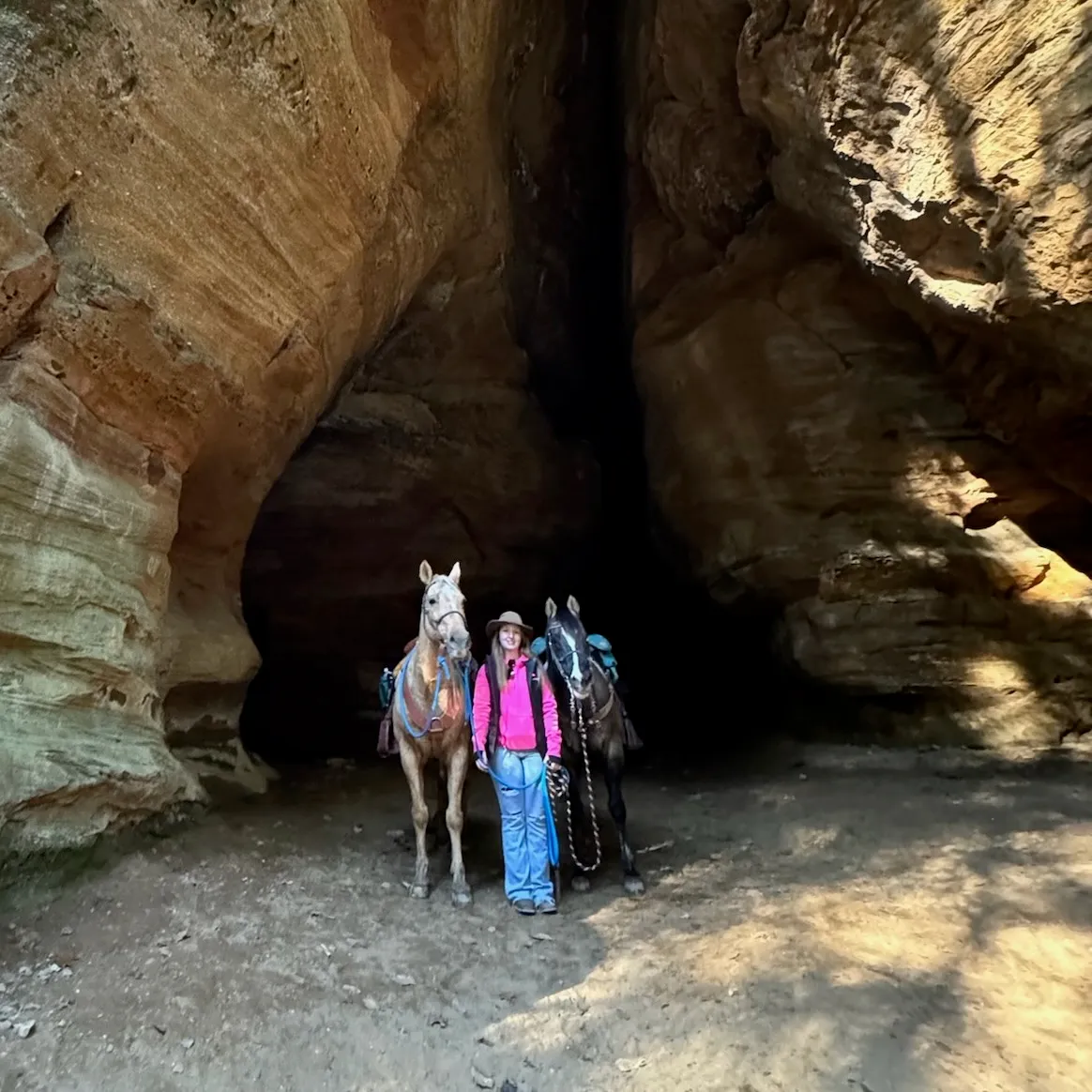 Brandi of Sun & Stone with two horses at the mouth of a sandstone canyon